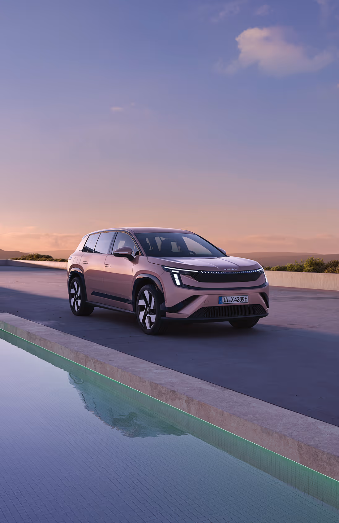 Frontalansicht des Škoda Elroq in der Farbe Timiano-Grün vor einem grünen Studiohintergrund. Die LED-Matrix-Scheinwerfer des Fahrzeugs leuchten und betonen das moderne Design der Frontpartie.