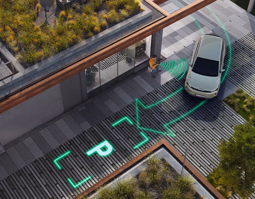 Animation des Trainierten fernbedienten Parkens: Leuchtend grüne, grafisch eingeblendete Linien, ein "P"-Symbol und Signalwellen visualisieren die Assistenzfunktion. Ein Pfeil markiert dabei den automatisierten Fahrweg des Fahrzeugs exakt in die zuvor gespeicherte Parklücke, während eine Person das Rangiermanöver von außen über ihr Smartphone steuert.