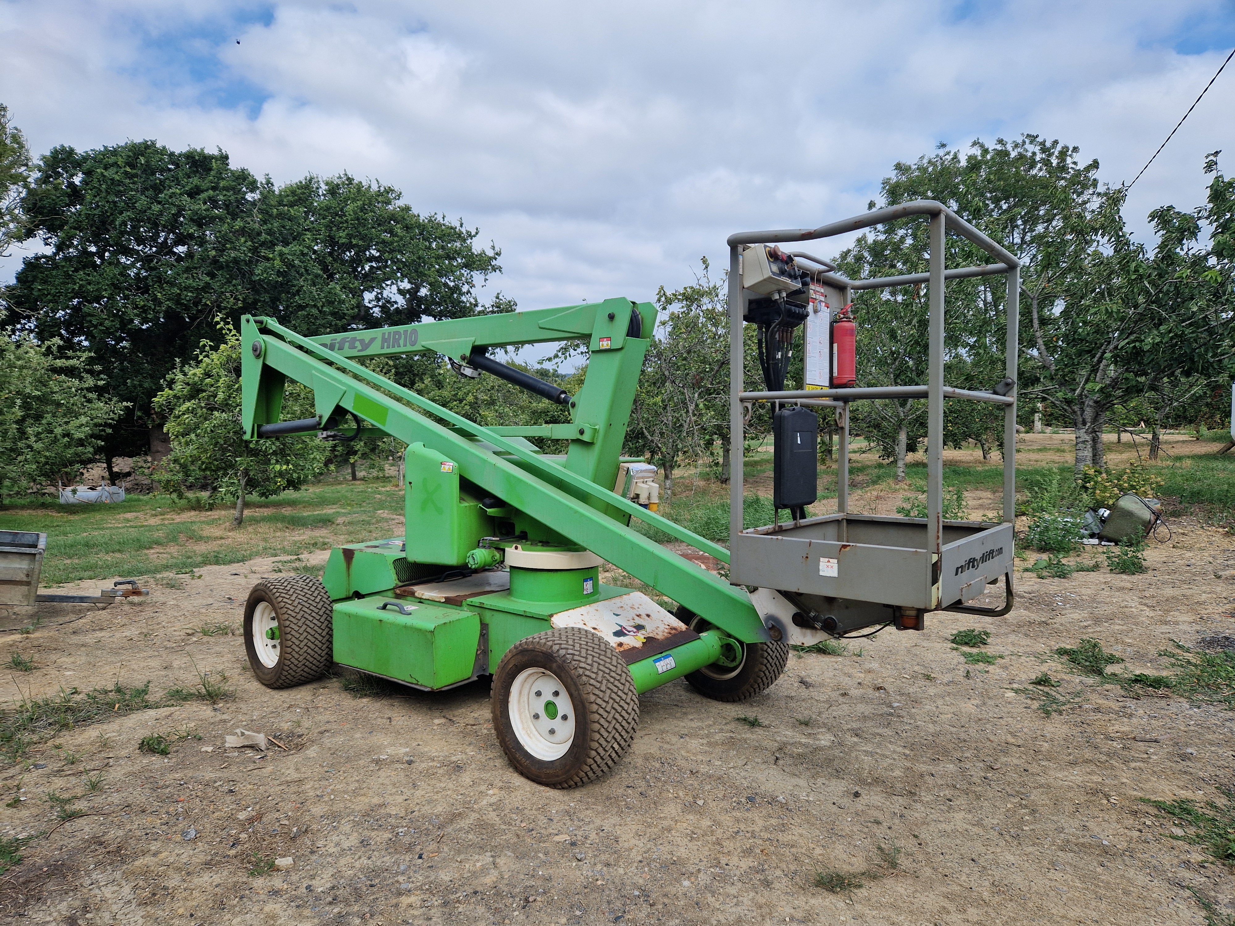 All-terrain vehicle towing a small wagon with four blue seats on grassy field with trees.