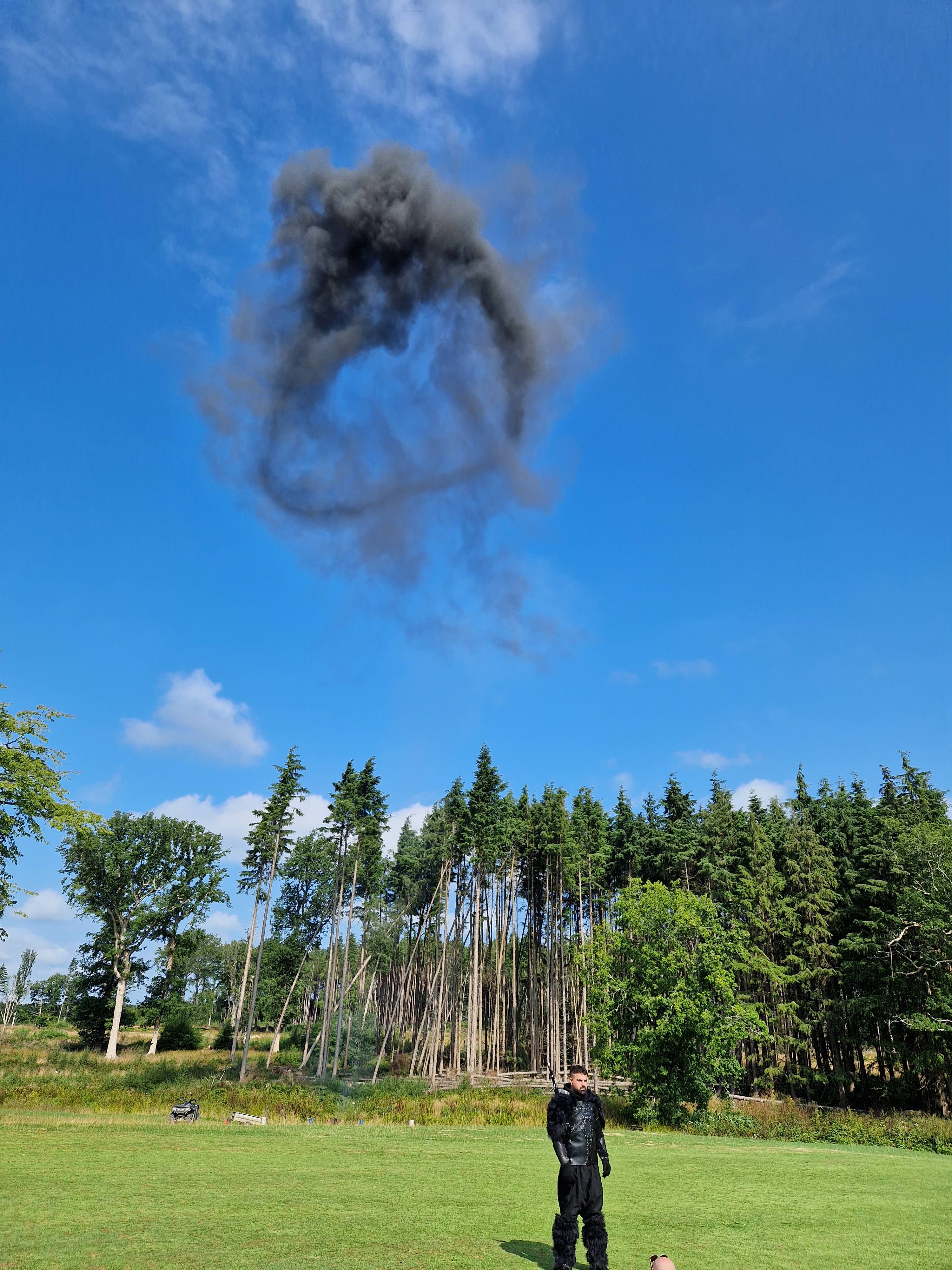 Shot of a actor on a field after a background explosion, with smoke trailing into the air.
