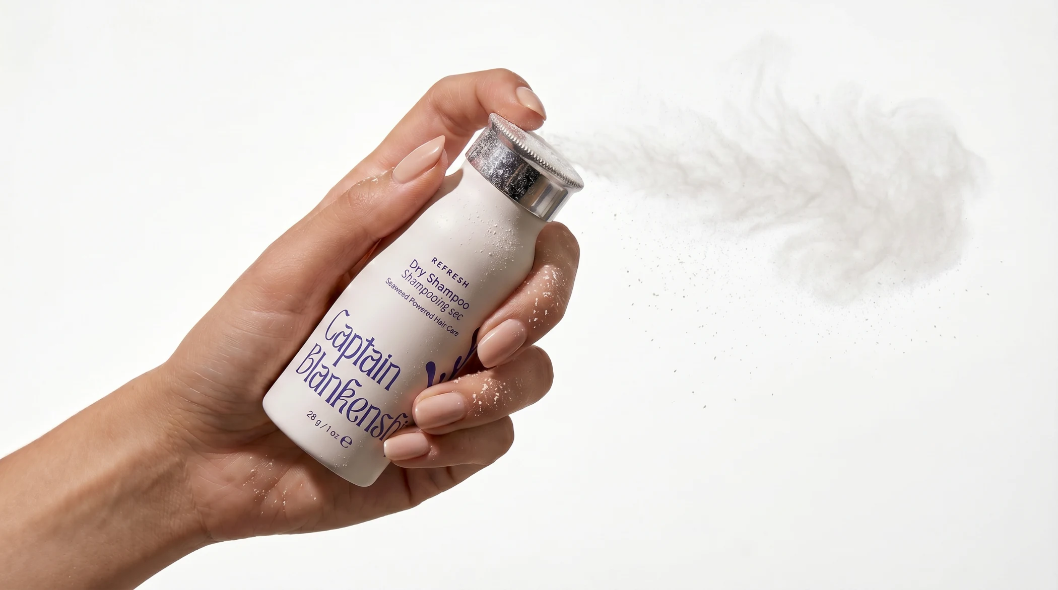 Hand spraying Captain Blankenship dry shampoo with powder mist against white background.