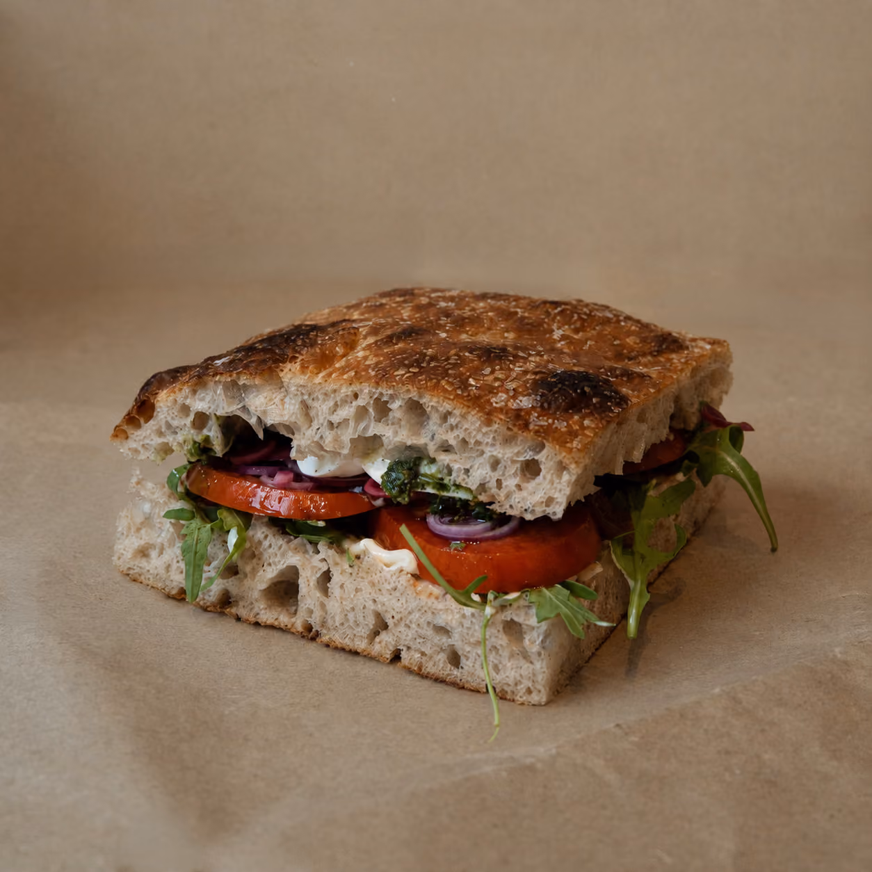 "En Karen" sandwich - Marinerede skiver af franske tomater, burrata, basilikumpesto, mayo, syltet rødløg, frisk rødløg og rucola.