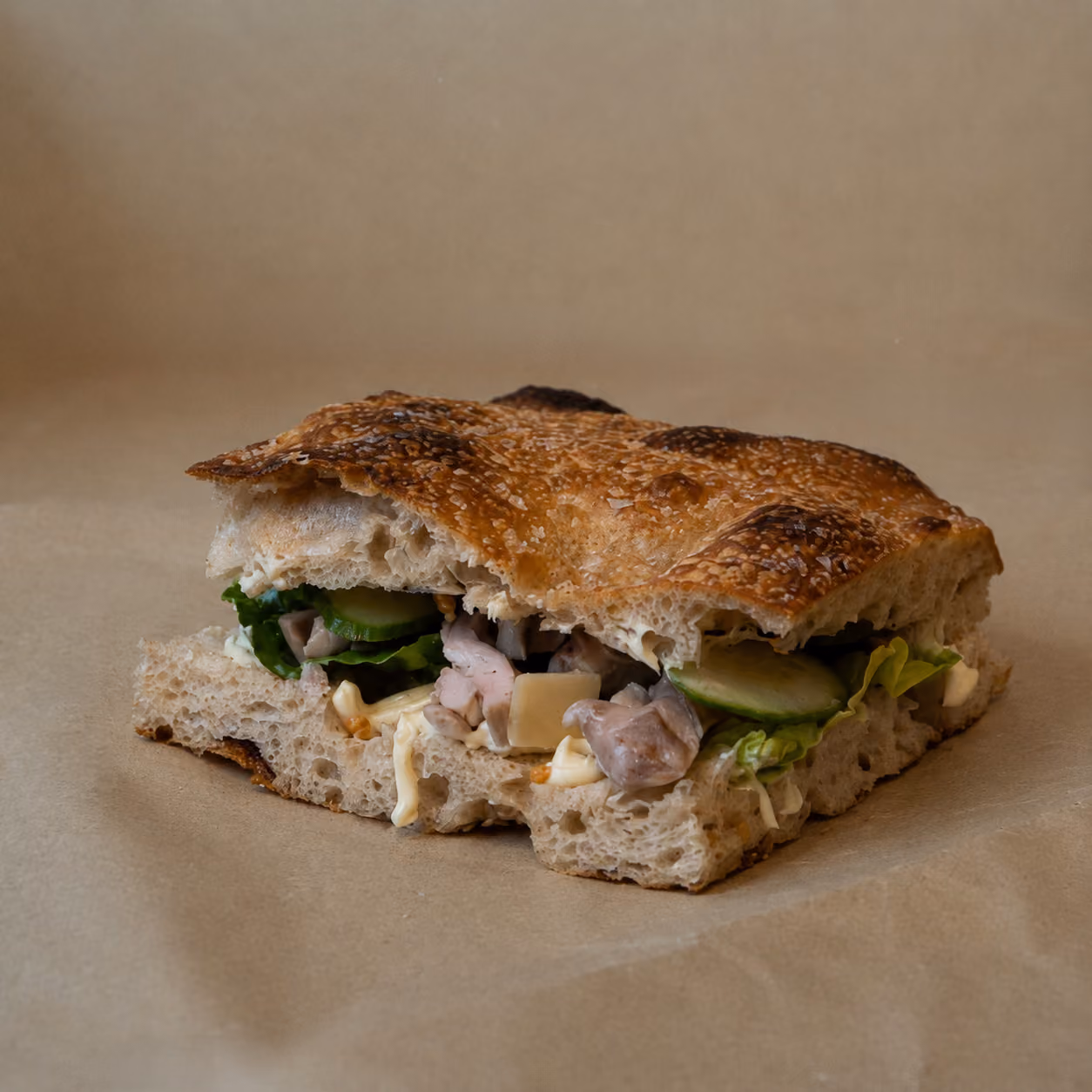 "En Mikkel" sandwich - Stegt kyllingeoverlår, parmesanflager, caesardressing, surdejscroutoner, hjertesalat og agurk.