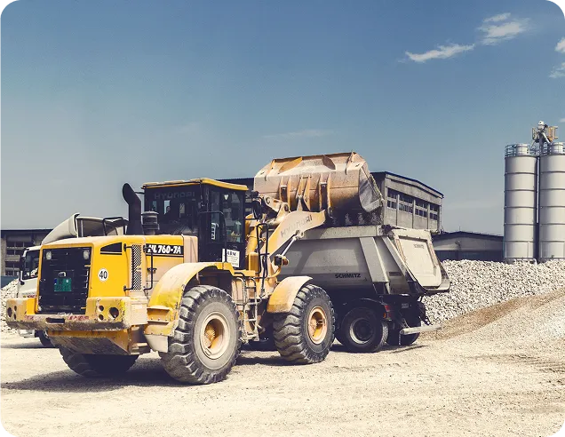 Yellow Hyundai wheel loader loading gravel into a dump truck at a construction site.