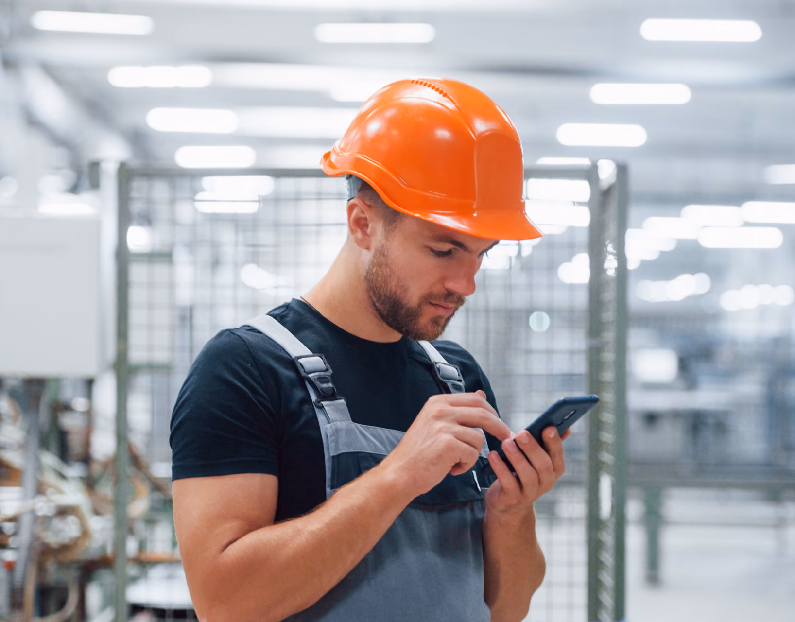 Worker in a hard hat taking a payment on his phone