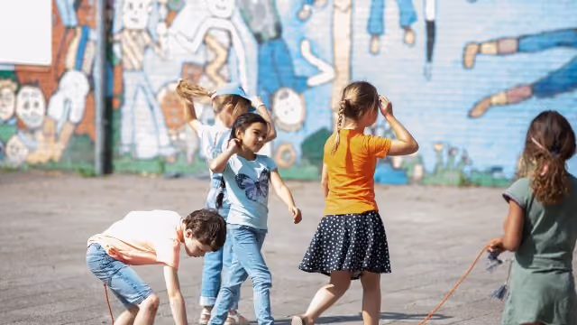Kinderen spelen buiten op een zonnige dag voor een muurschildering.