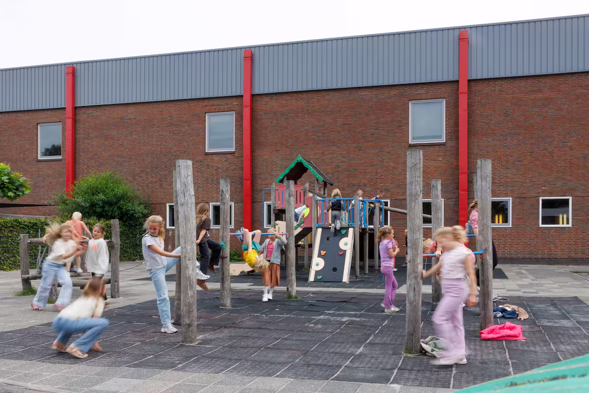 Kinderen spelen actief op een klimrek en houten speeltoestellen op een schoolplein.