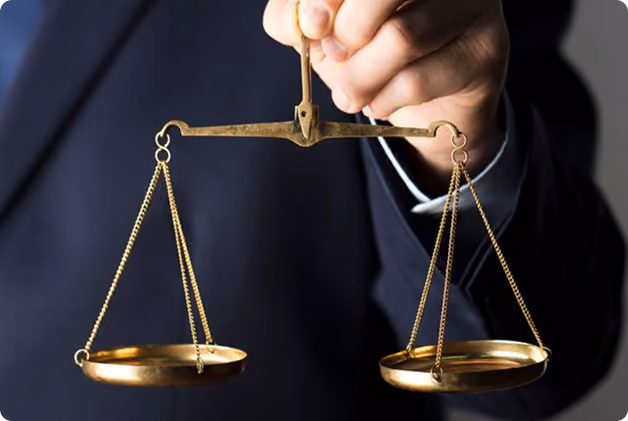 Hand in suit holding a brass balance scale with empty pans.