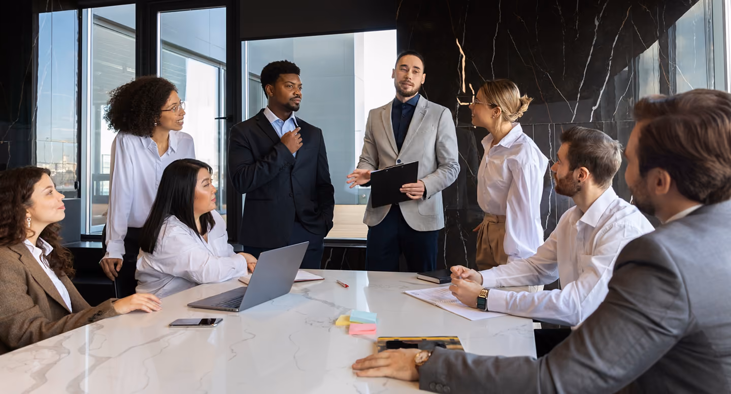 Business team in a modern office having a discussion around a conference table with a laptop.