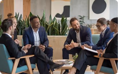 Diverse group of six business professionals engaged in a meeting in a modern office lounge.