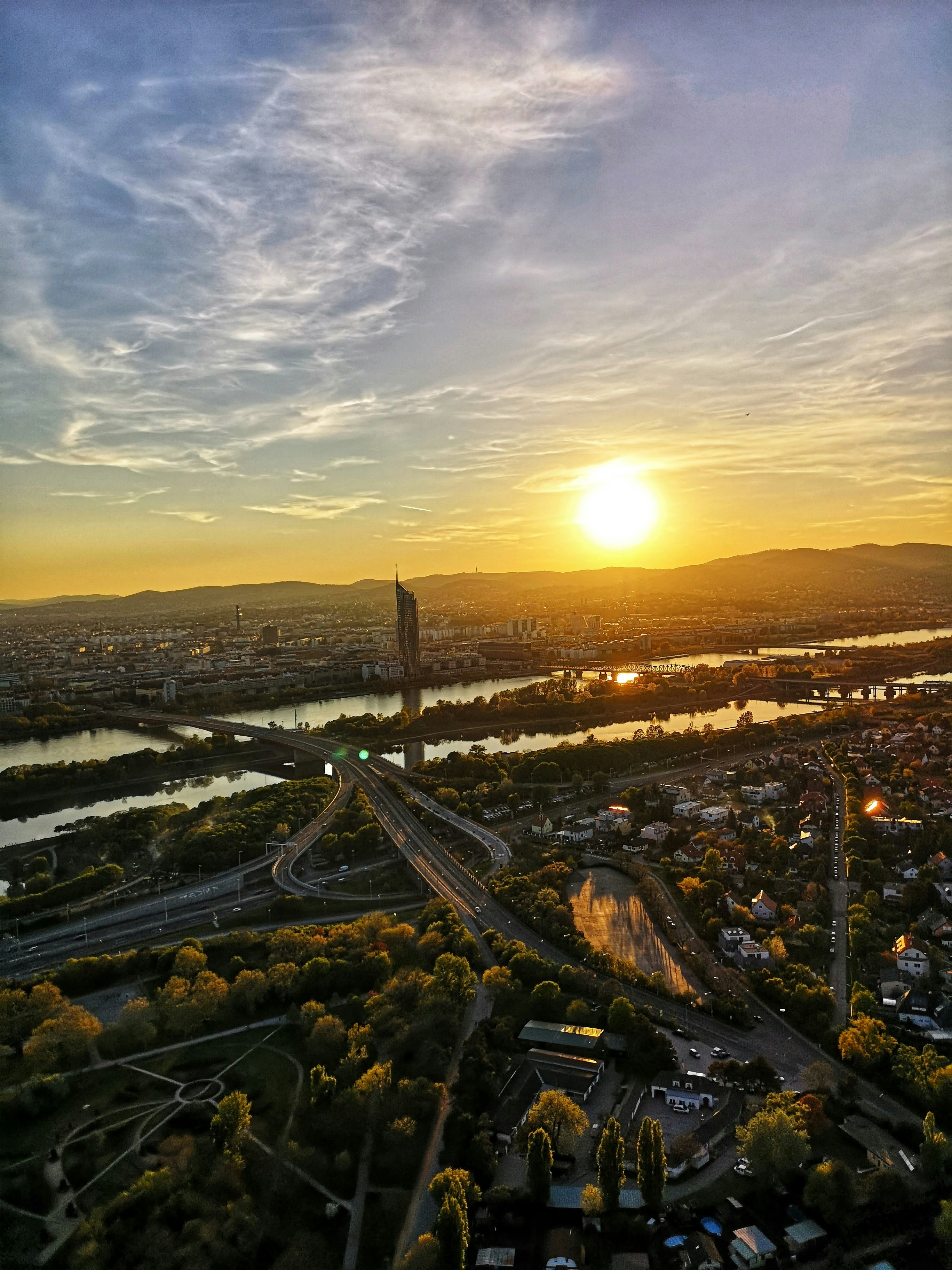 Vienna skyline at sunset, with the illuminated St. Stephen's Cathedral and a mountain range in the background.