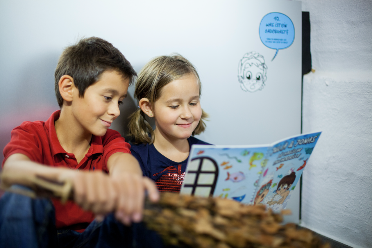 Zwei Kinder blättern gemeinsam in einem Ausstellungsbuch.