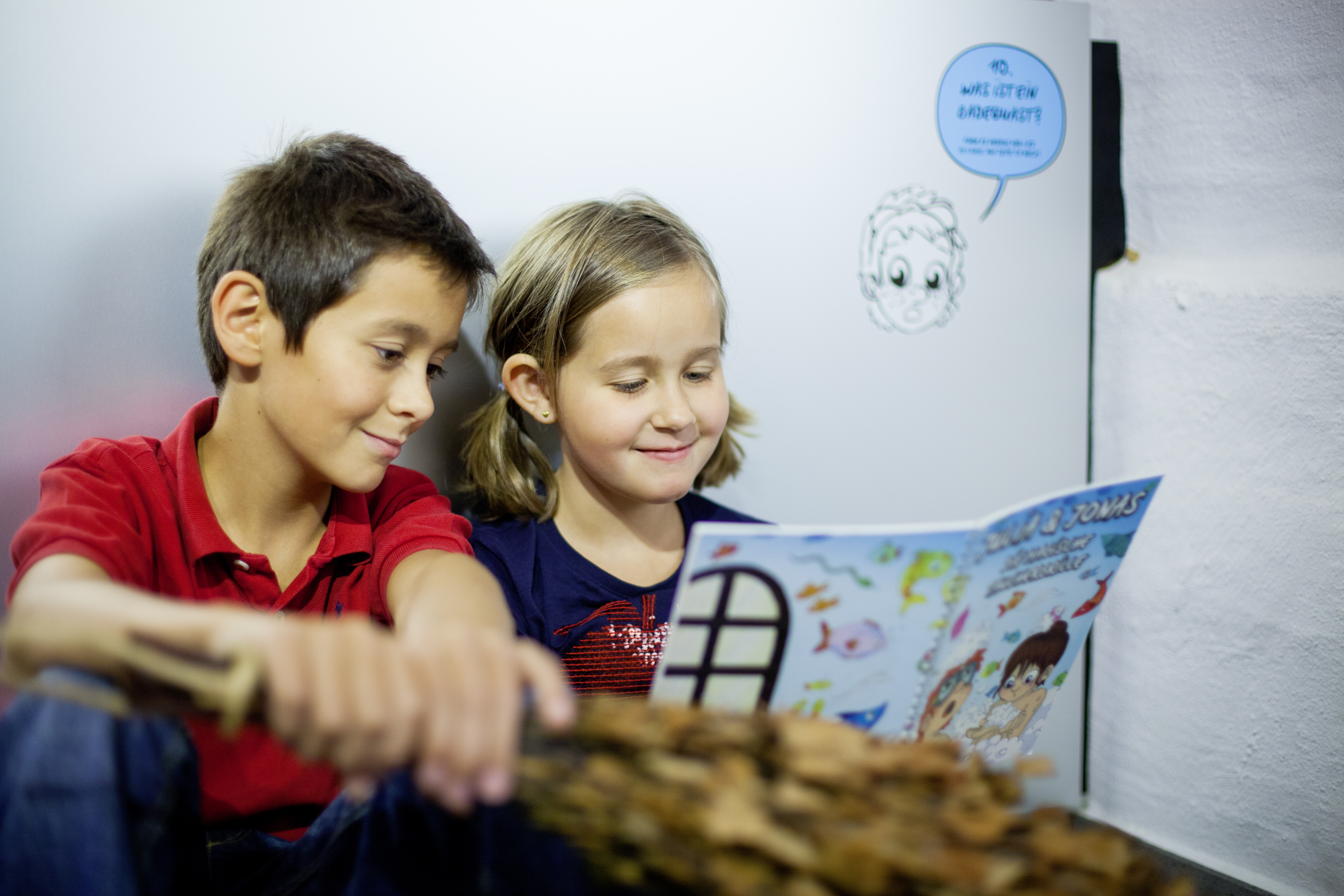 Kind und Mädchen lesen den Museumscomic „Die magische Taucherbrille“