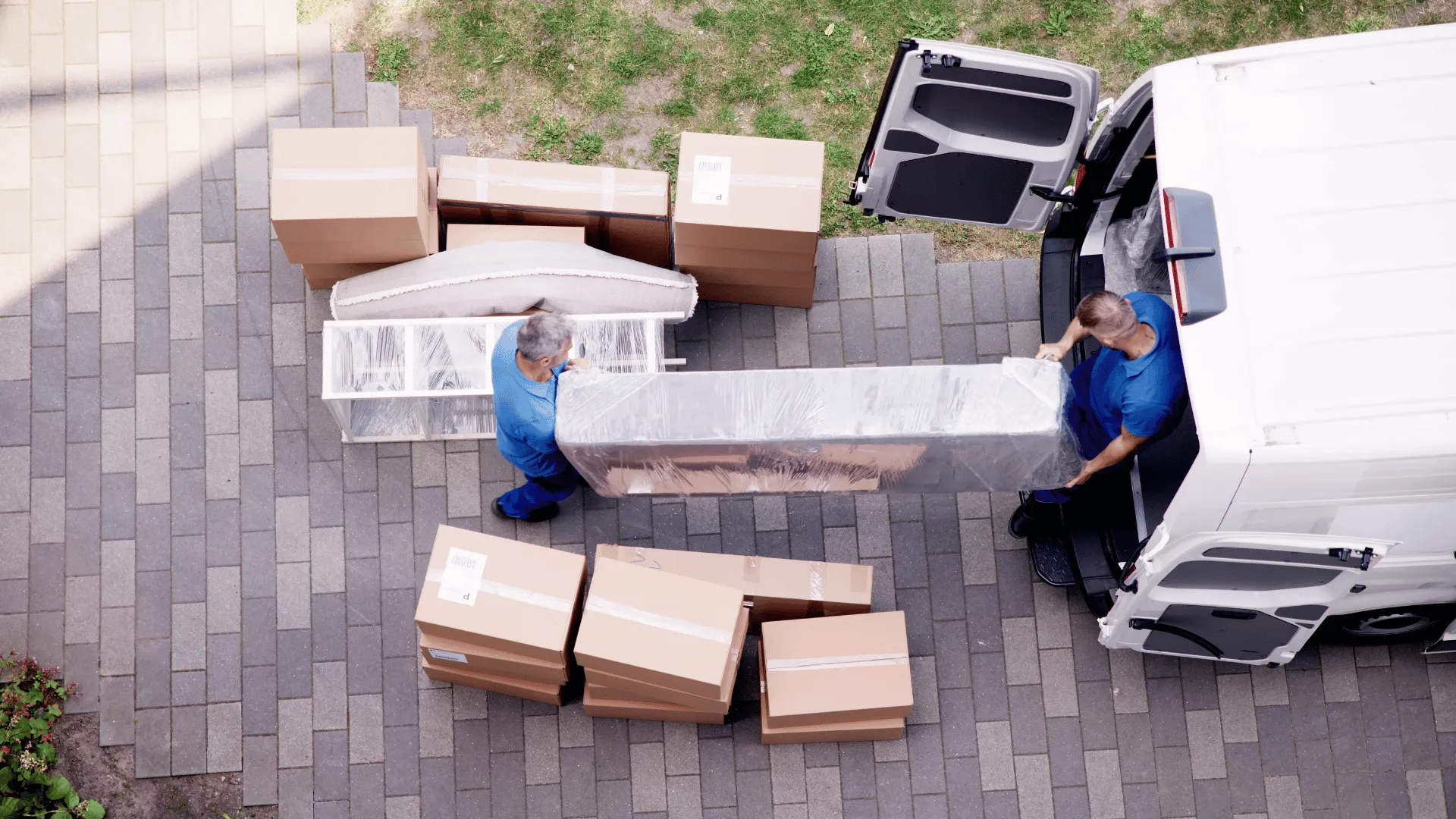 Umzugshelfer transportieren ein verpacktes Sofa und Umzugskartons