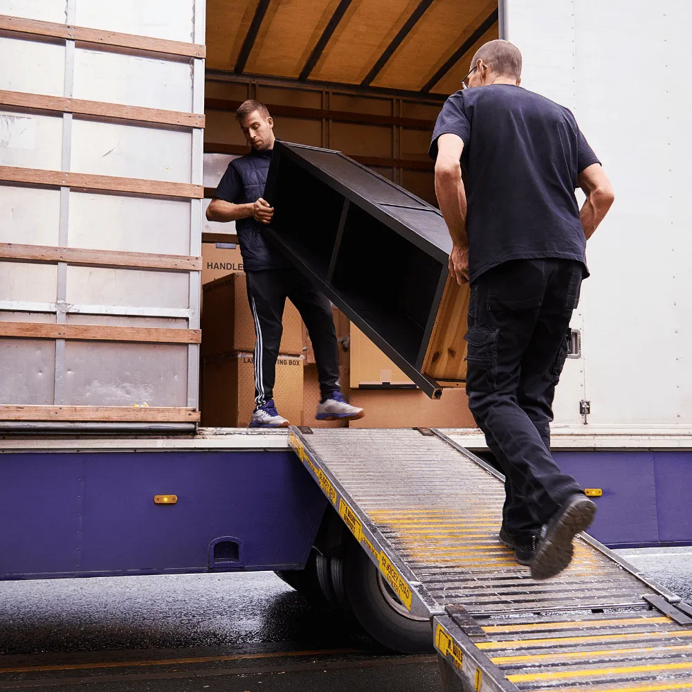 Umzugshelfer schiebt Transportgut über eine Laderampe in den Transporter