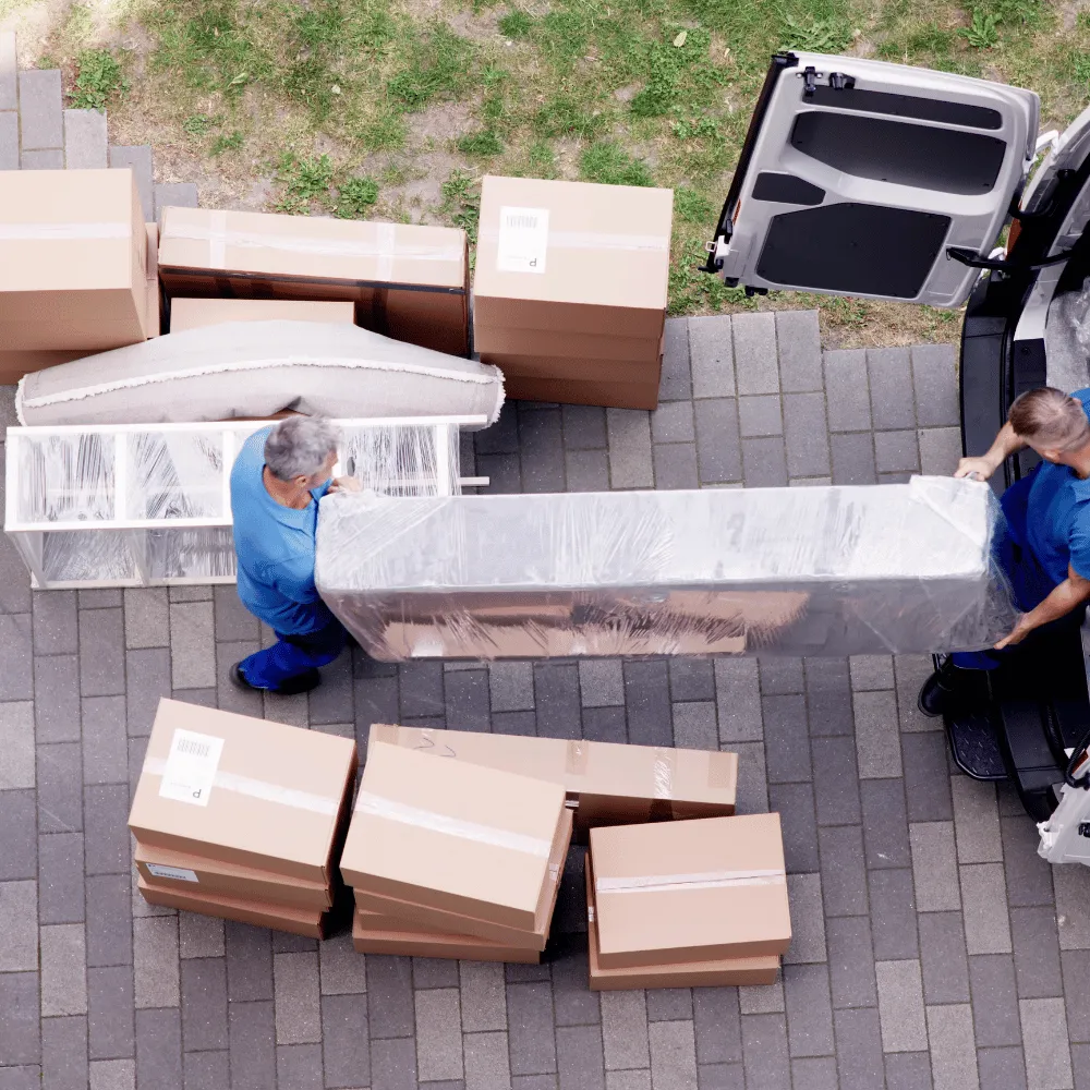 Umzugshelfer transportieren ein verpacktes Sofa und Umzugskartons