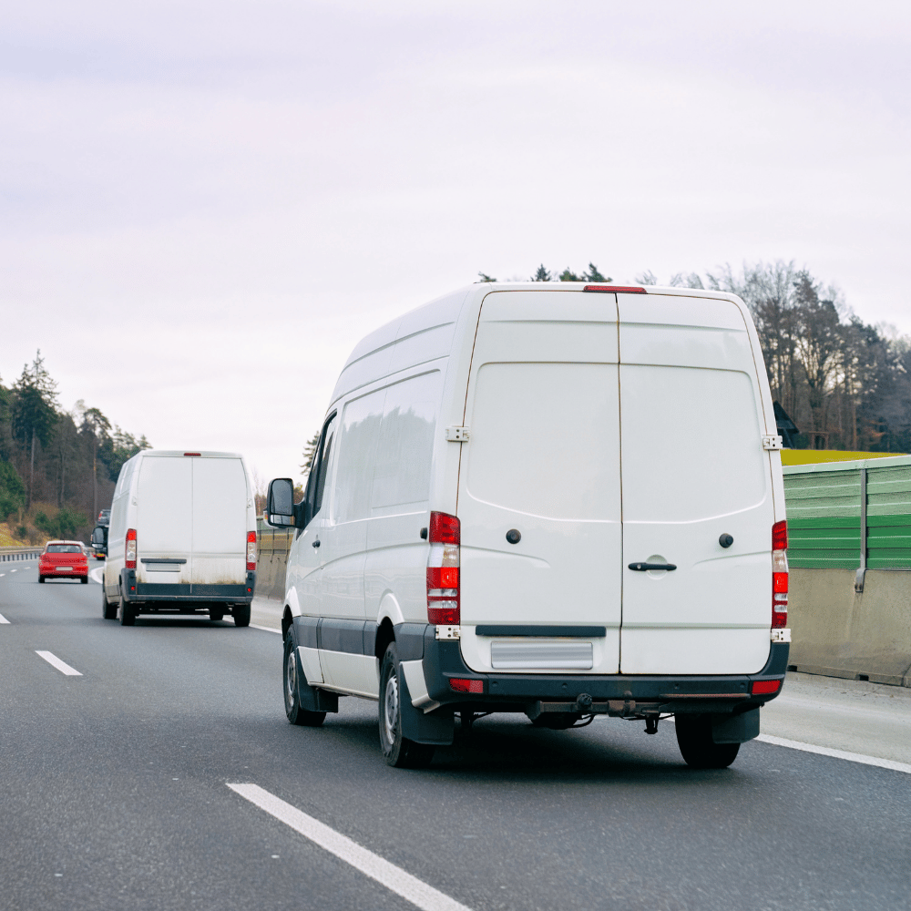 Zwei weiße Transporter fahren hintereinander auf der Autobahn