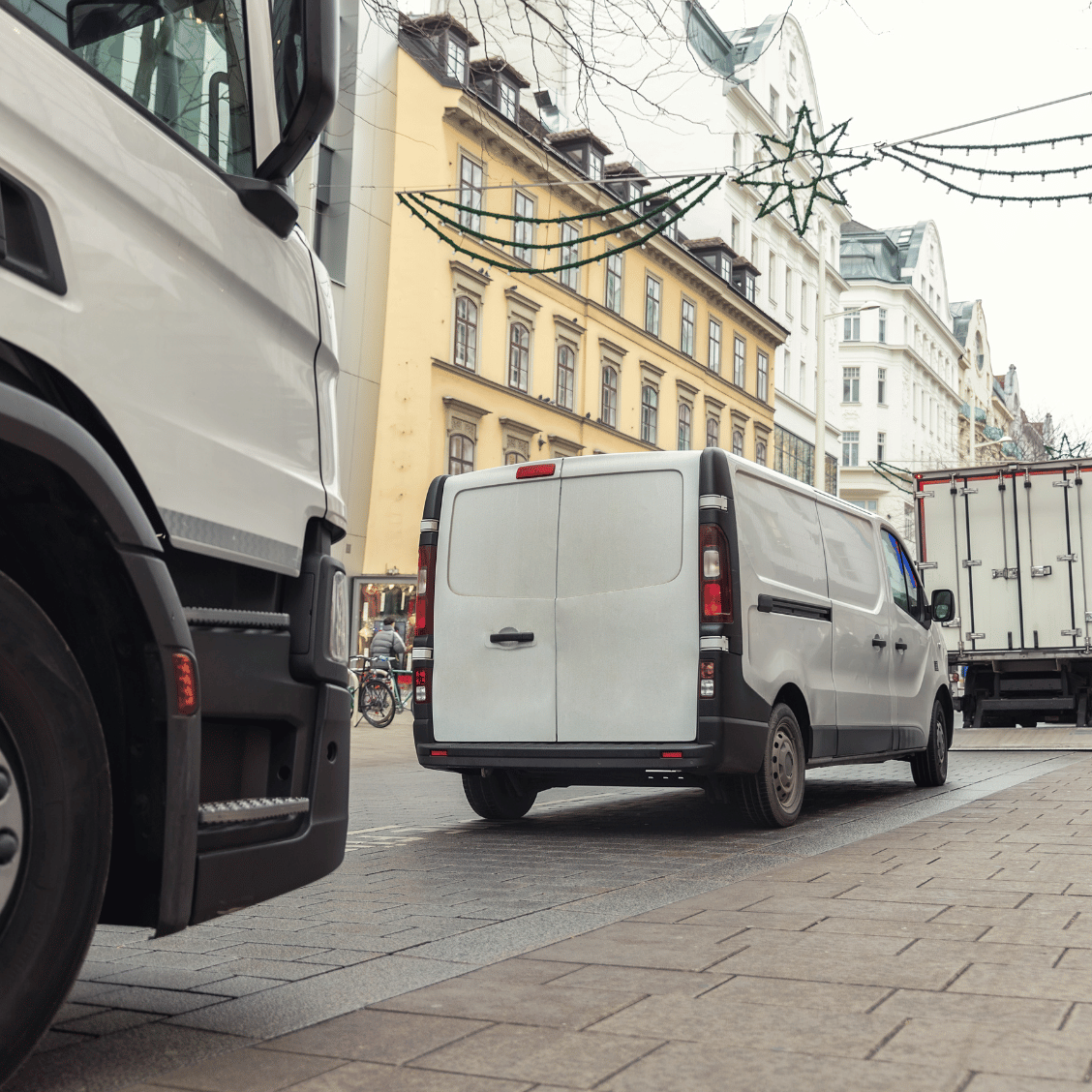 Lkw und Lieferwagen stehen auf einer schmalen Straße in einer Altstadt mit mehrstöckigen Wohnhäusern