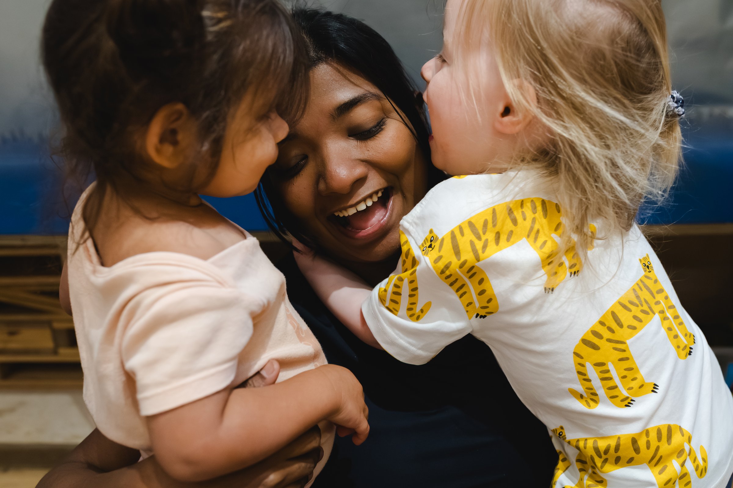 "Nursery teacher hugging two happy toddlers at Hatching Dragons nursery"