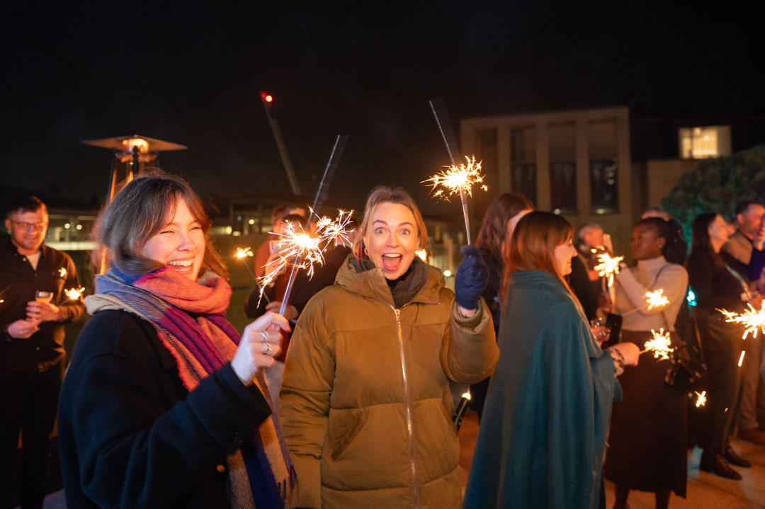 People outdoors at night happily holding sparklers during a festive celebration.