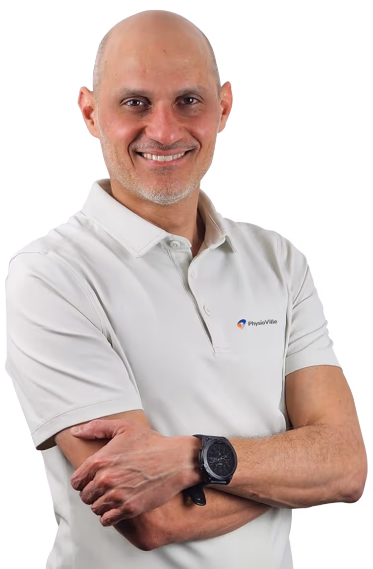 Smiling bald man in white PhysioVille polo shirt with arms crossed wearing a black wristwatch.