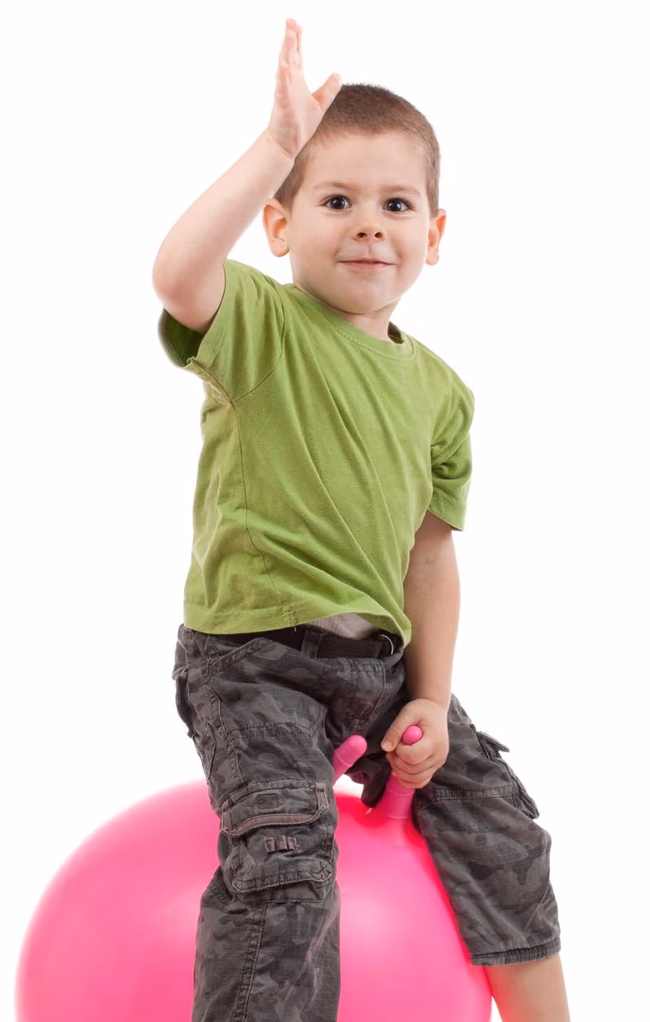 Young boy in green shirt sitting on a pink hopper ball, raising one hand in Physioville -Physiotherapy clinic in Ottawa