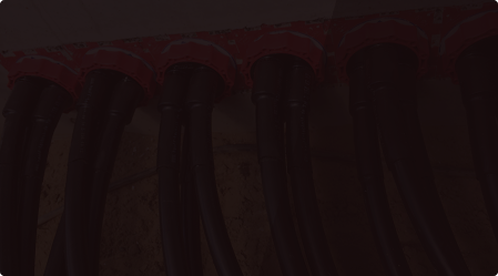 Six black electrical cables connected to a red terminal block on a wall.