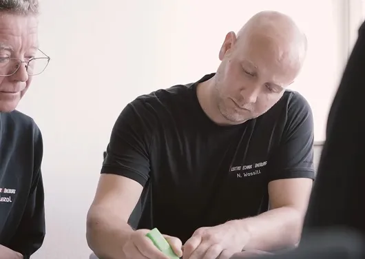 Mann mit Glatze markiert mit grünem Textmarker auf Papier, andere Person schaut zu.