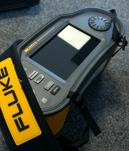 Fluke 1674 FC Multifunction Tester with screen and buttons on a gray surface.