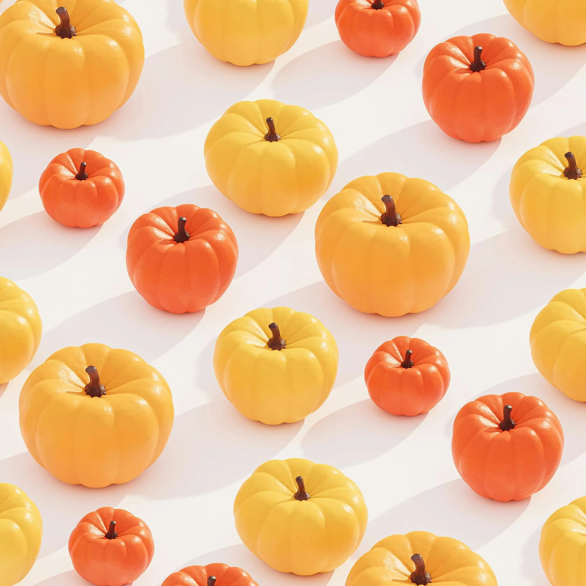 Pattern of small orange and yellow pumpkins casting shadows on a white surface.