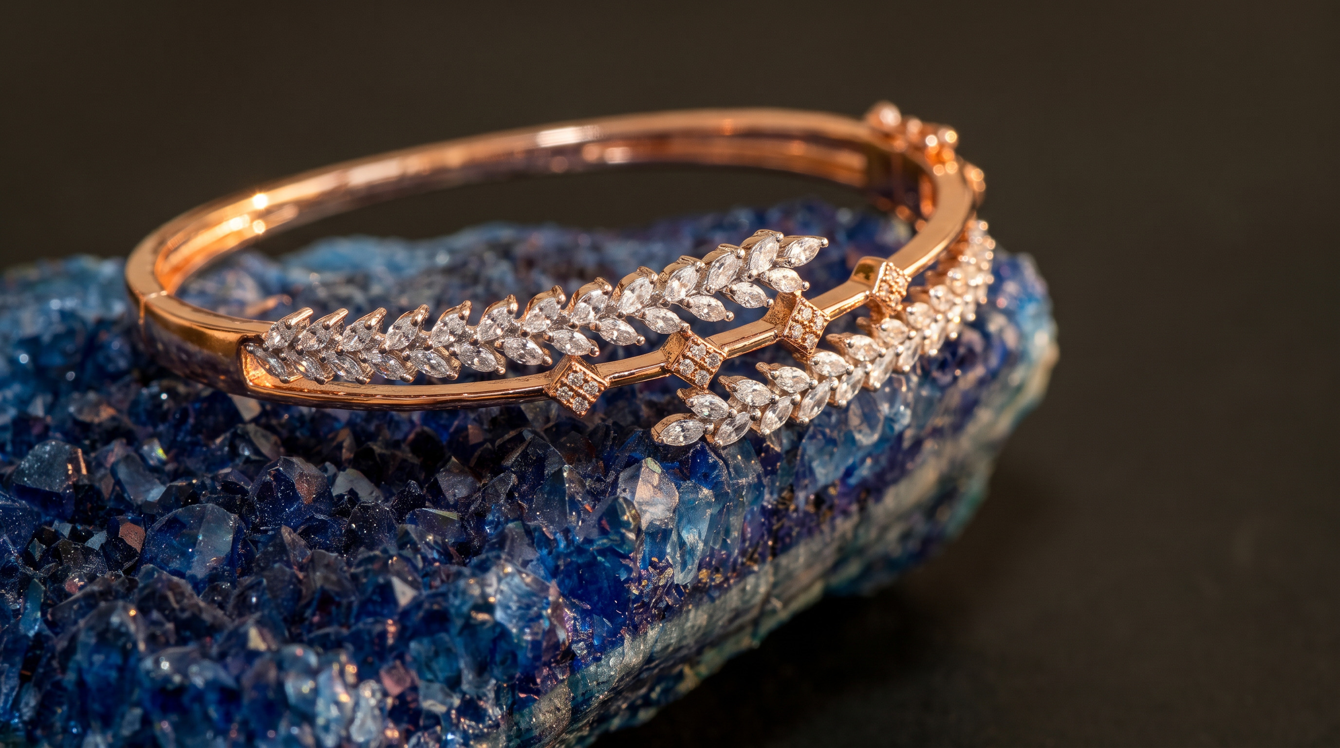 Rose gold bracelet with leaf-shaped diamonds resting on a blue crystal rock.