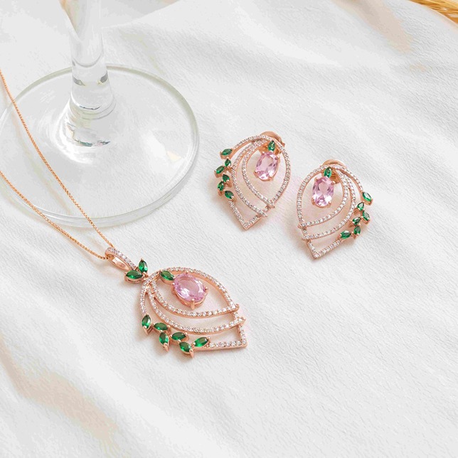 Rose gold necklace and earrings with pink oval gems, small green leaf-shaped gems, and diamonds.