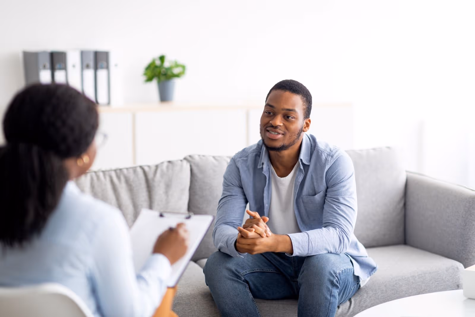A man sitting on a couch talking to a woman.