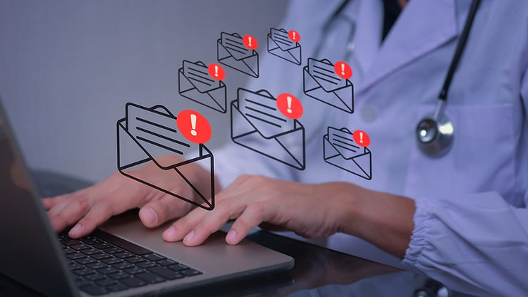 Doctor typing on a laptop with overlaid icons of envelopes and exclamation marks, suggesting phishing emails.