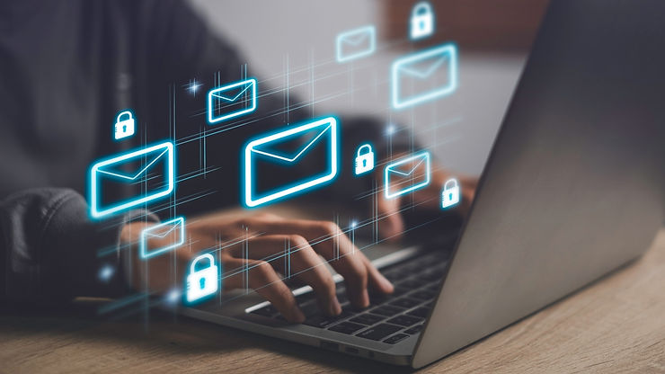 Hands typing on a laptop with glowing email and lock icons floating above. The setting is a wooden desk, suggesting digital security.