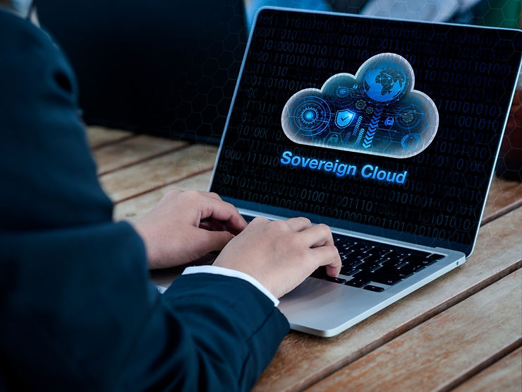 Hands typing on a laptop displaying a digital cloud with "Sovereign Cloud" text. Background shows binary code and a wooden table.