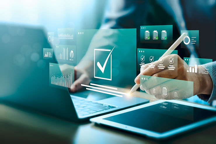 Person uses a stylus on a tablet, overlaying digital checkmarks and charts. Blue-green tones, modern tech setting, focus on data visuals.