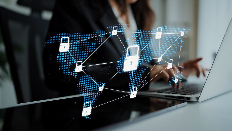 Person typing on a laptop, overlaid with digital padlocks connecting a world map. Image conveys cybersecurity. Blue and white tones dominate.