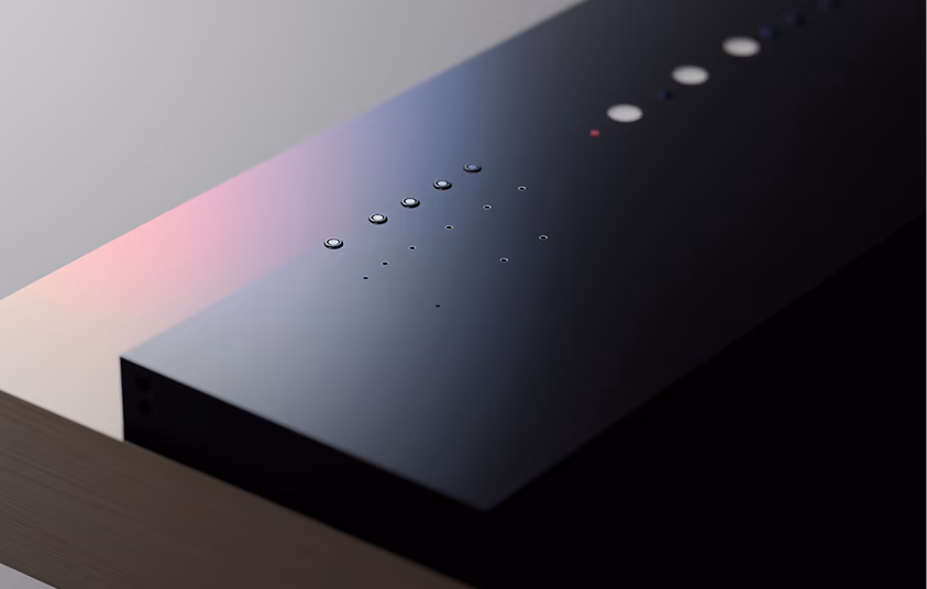 Close-up of a sleek black device with water droplets on its surface on a wooden table.