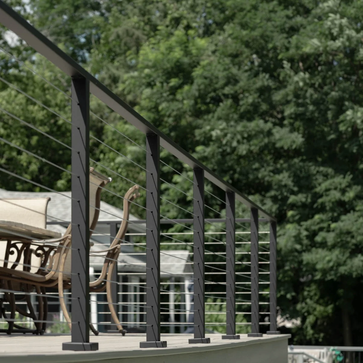 Black tapered posts carry fine horizontal infill along a curved deck edge under summer trees