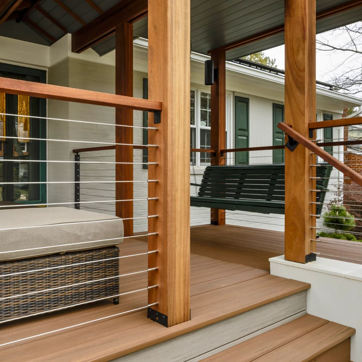 Wood porch posts take stainless rod infill on DriveTite mounts, a black swing hanging beyond