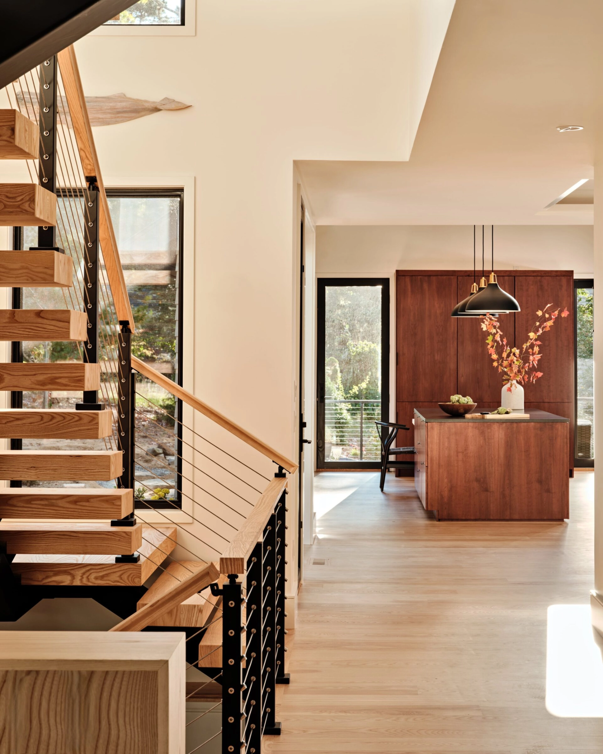A U-shaped FLIGHT Mono stair with cable railing beside a walnut kitchen