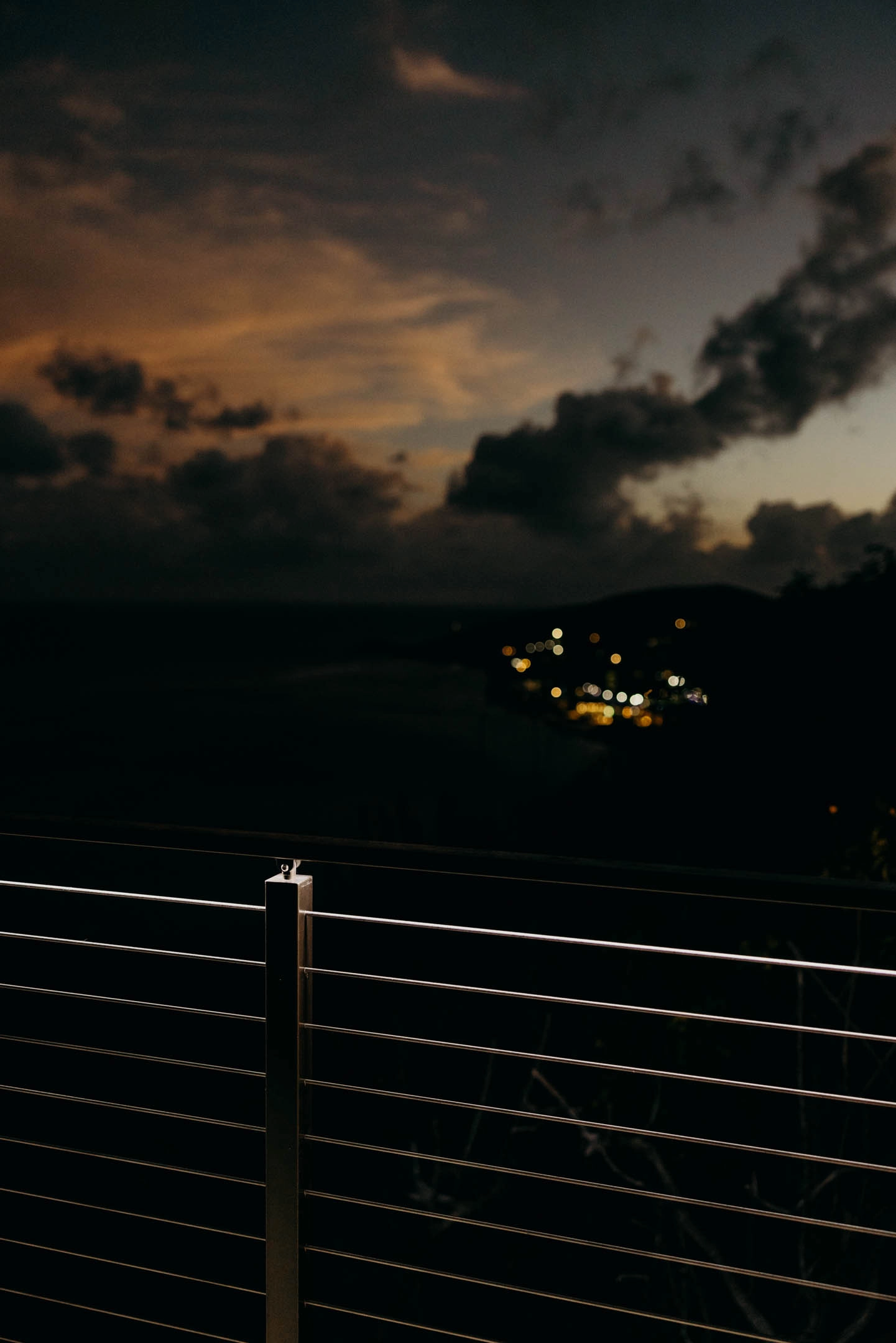 A Signature Rod post catches the last light, distant town lights below at dusk