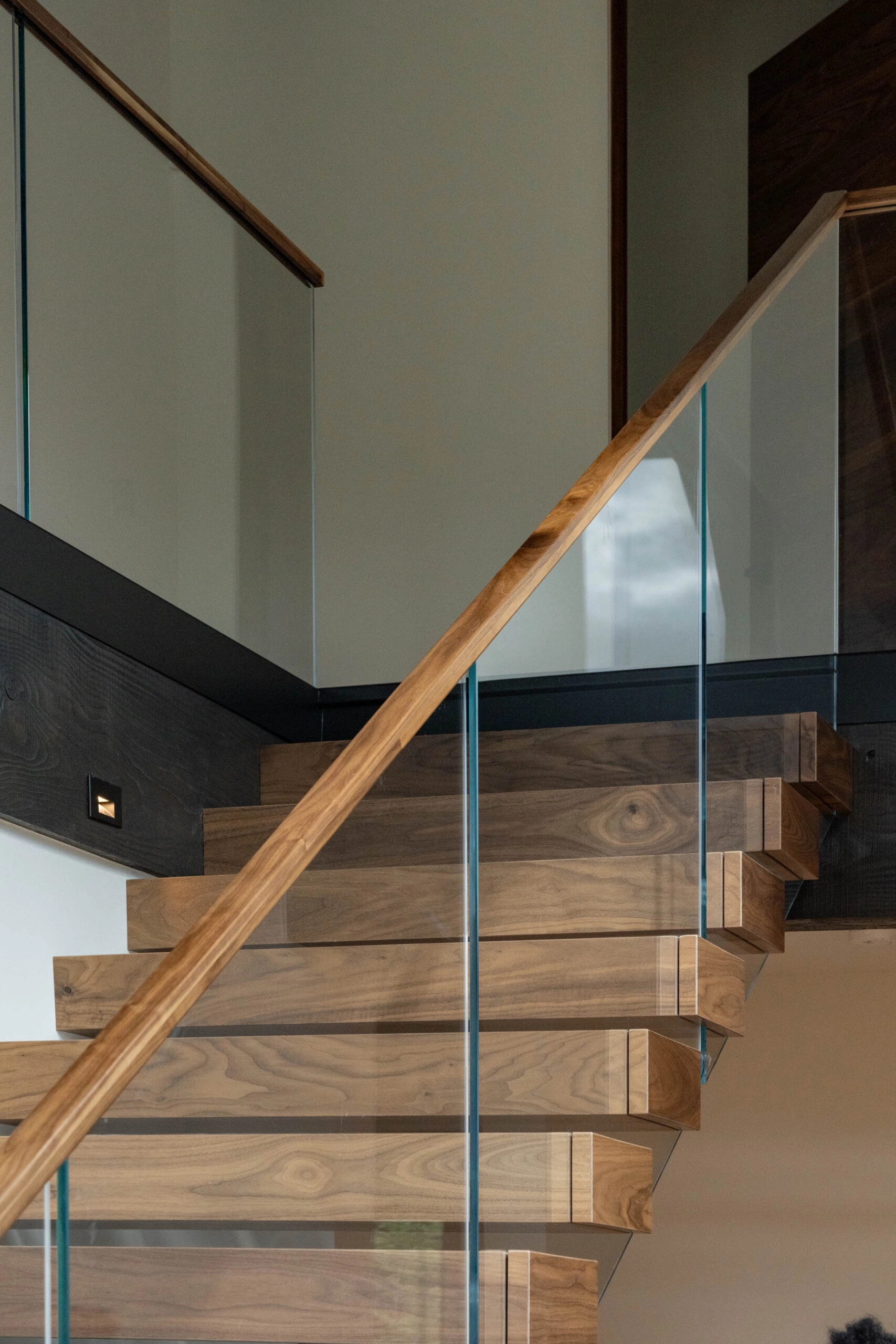 Chunky wood treads pass behind glass rising from a Recessed Base Rail on the landing