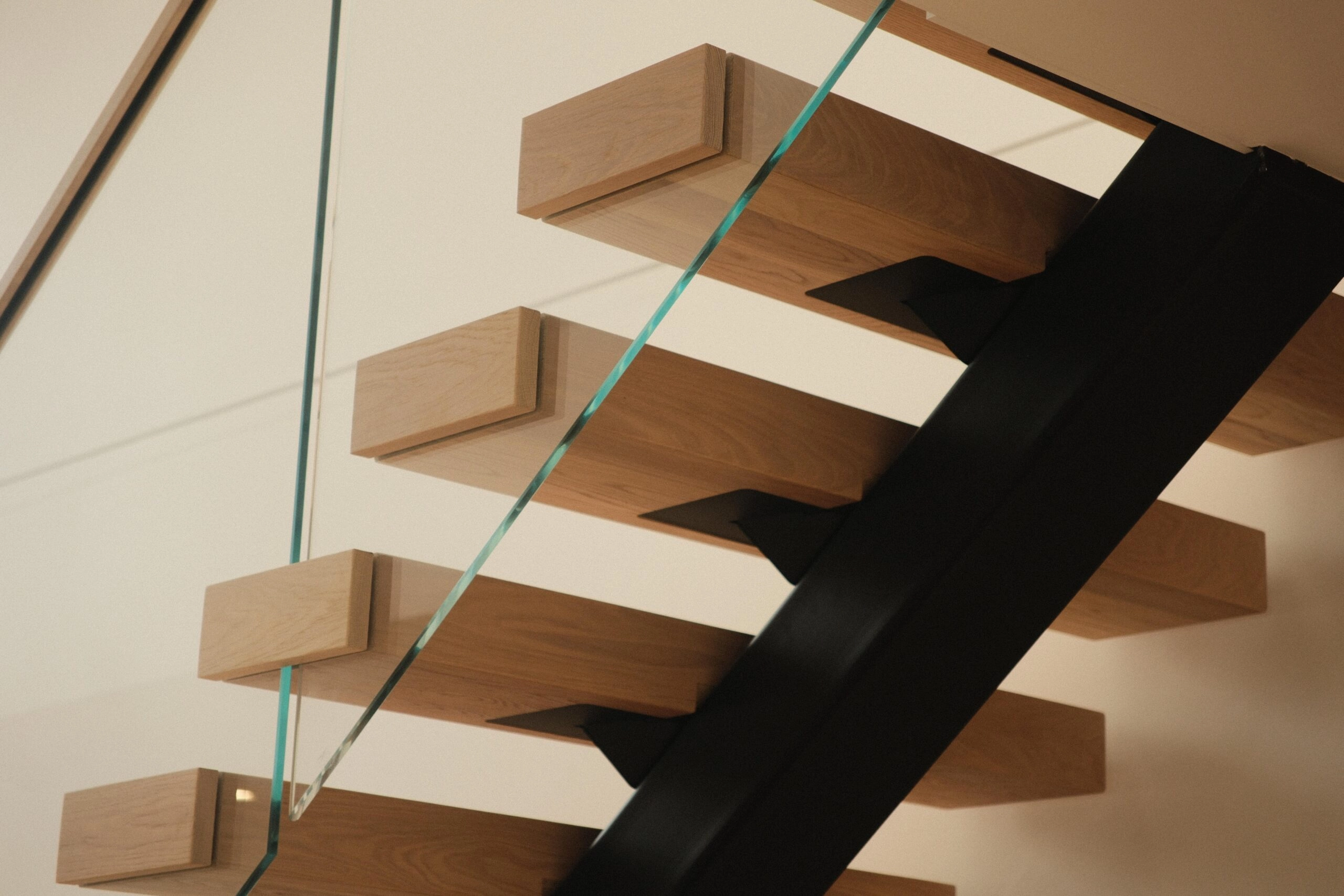 Oak treads seen from below, fixed to the black FLIGHT Mono stringer behind glass