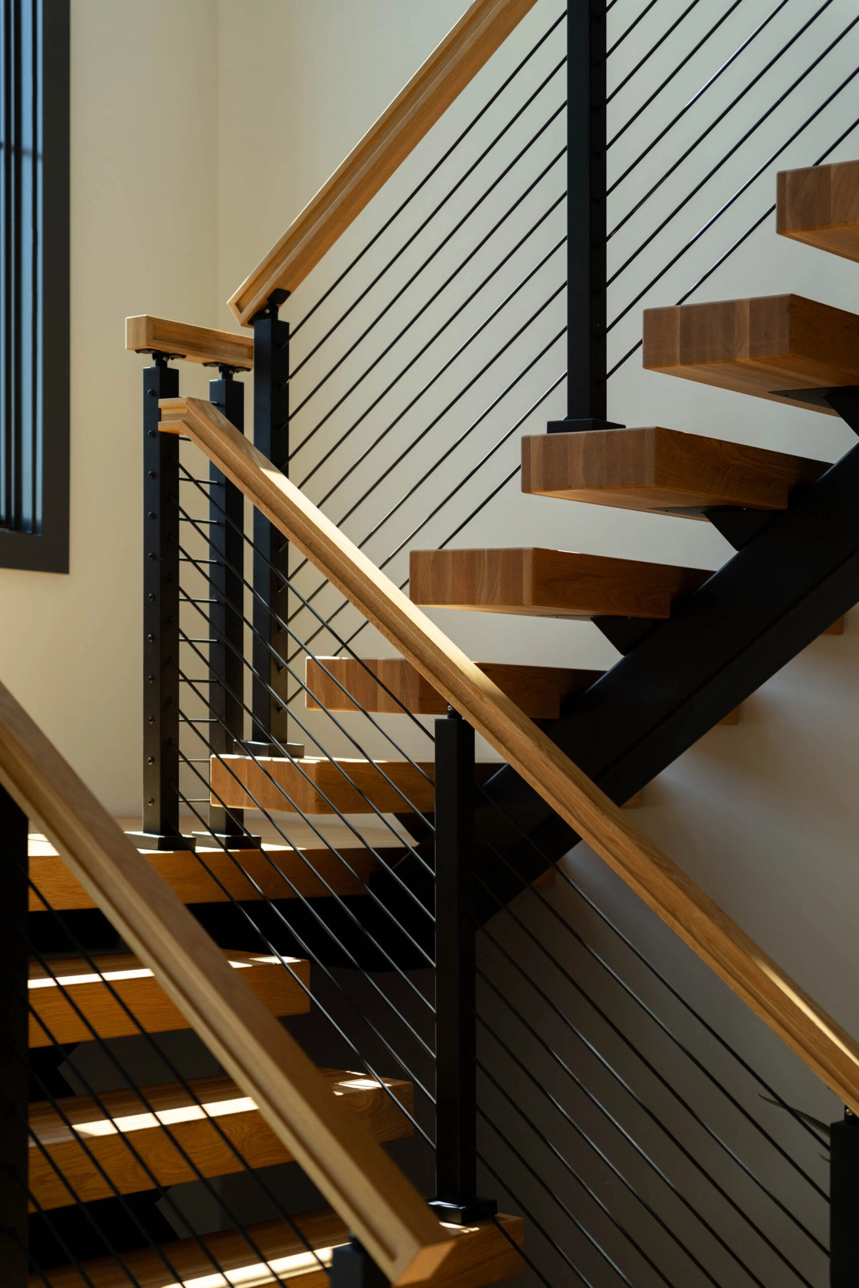 Rod railing and a wood handrail run alongside sunlit FLIGHT Mono treads