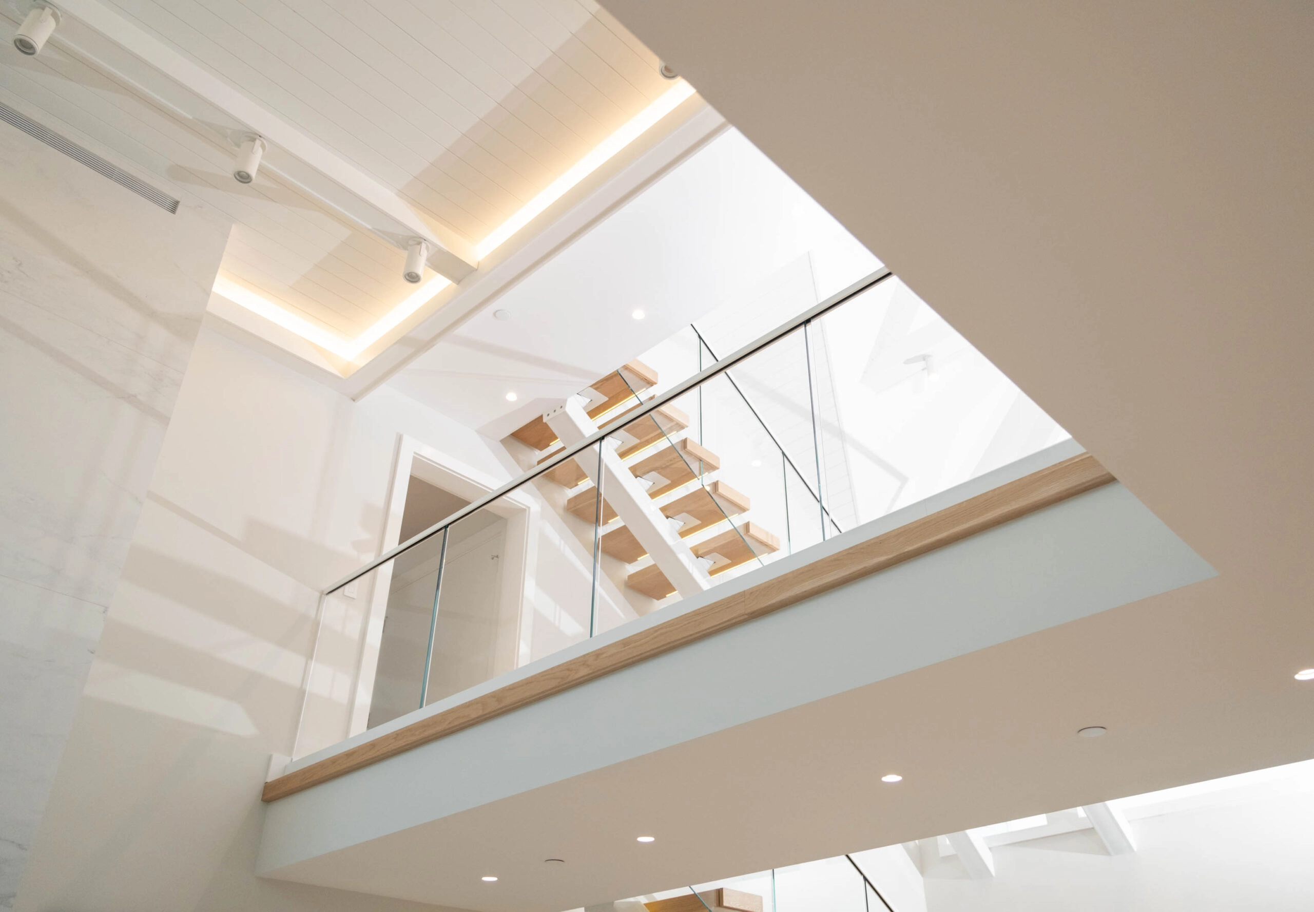 Looking up at a loft edged in Vedera glass and Base Rail, a floating stair beyond