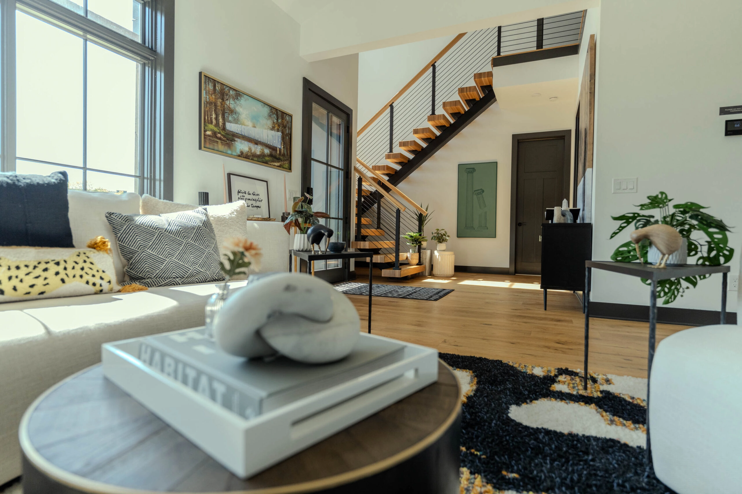 A living room with a coffee table and rug, FLIGHT Mono stair with rod railing beyond