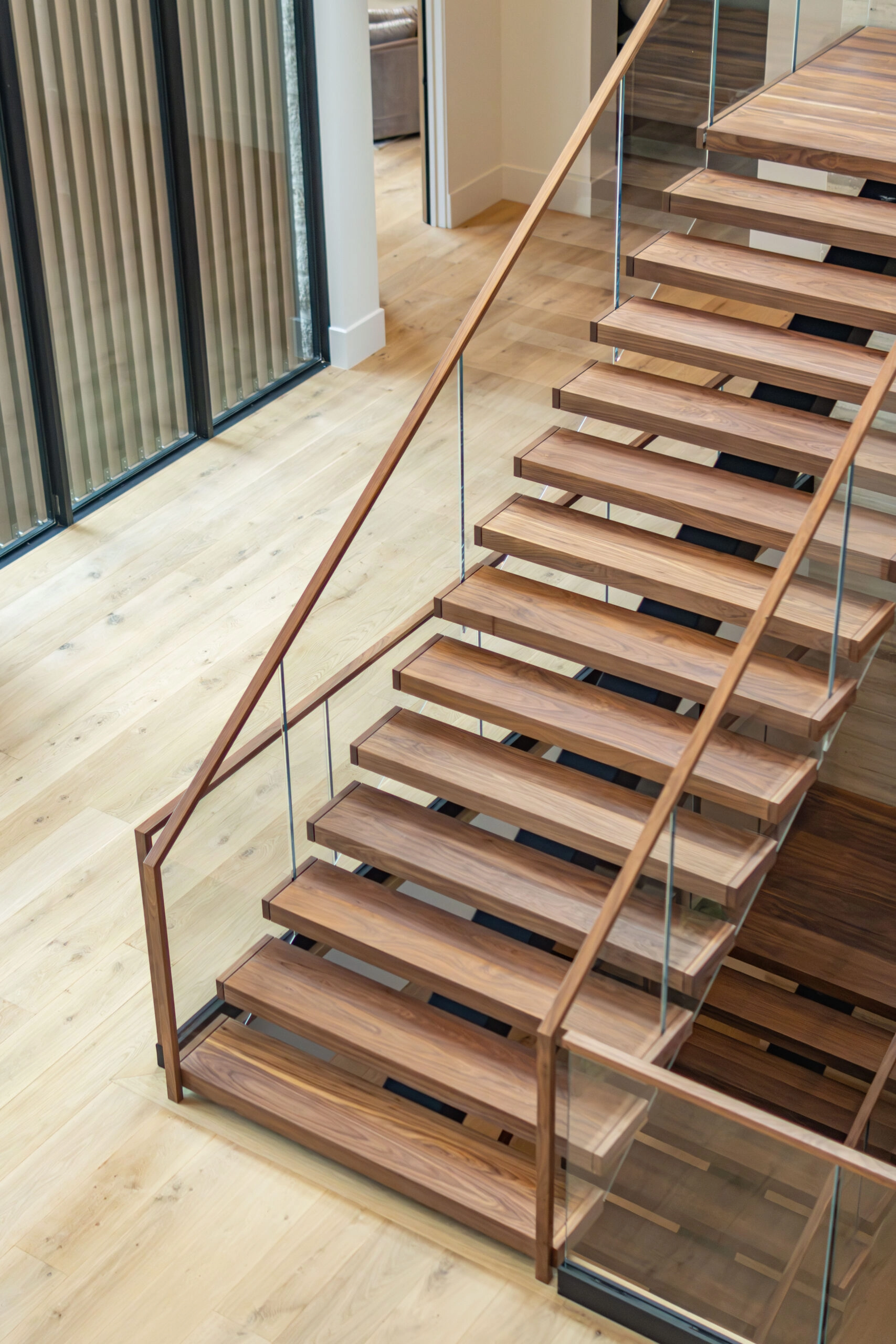 Walnut treads and a matching handrail on a FLIGHT Mono stair with glass railing