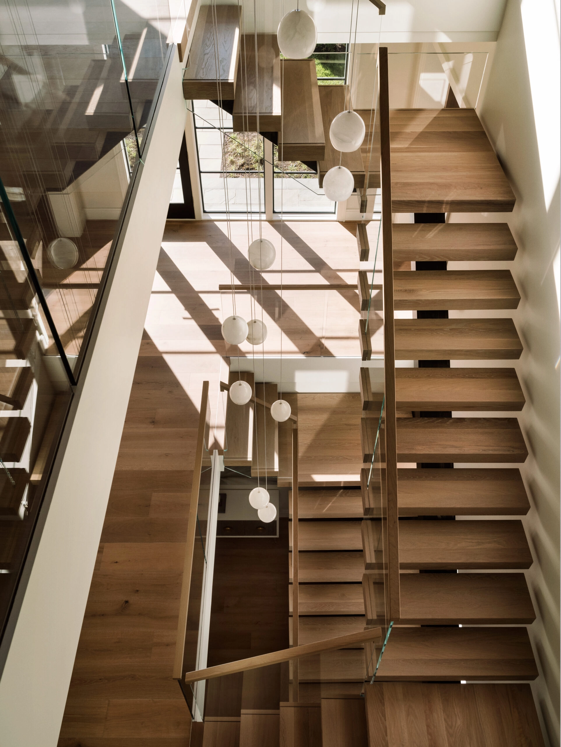 Sunlight stripes oak treads on a FLIGHT Mono stair seen from the landing above